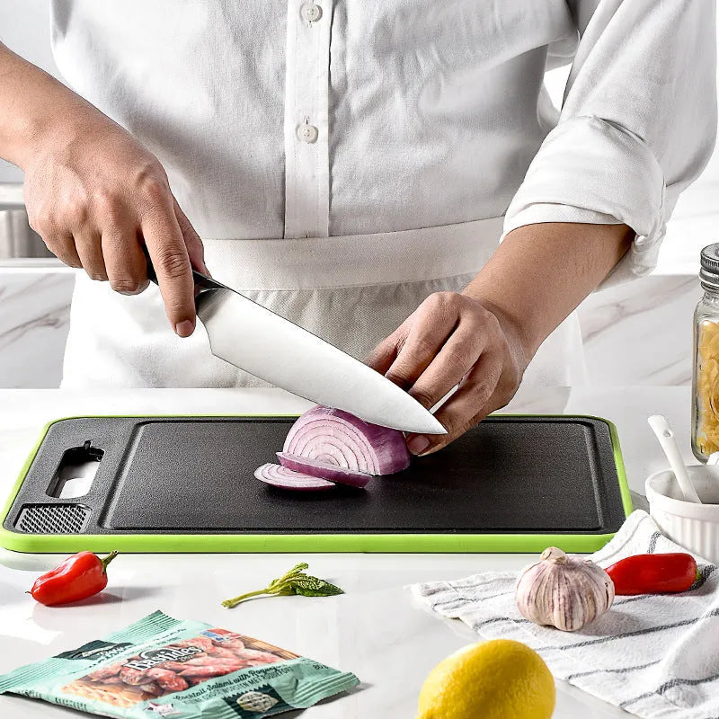Grey square aluminium cutting board with defrosting side, grinder teeth, and integrated knife sharpener.