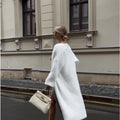 White oversized women's knit cardigan jacket with long line and regular sleeves.