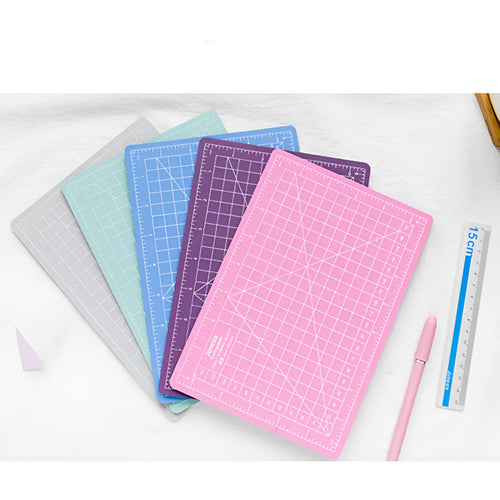 Art pen knife cutting board set showing plastic mat, metal ruler, sharpener and blade in assorted colours.