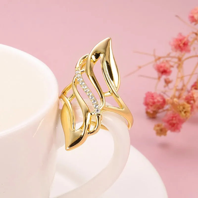 Gold women's ring with exaggerated curved design on a copper band, shown in casual style.