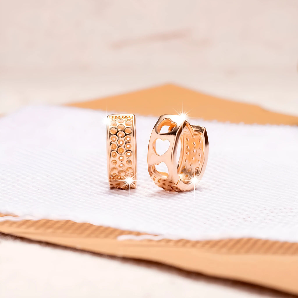 Close-up of a pair of rose gold circular hoop earrings with three small hollow heart shapes cut out of each band.