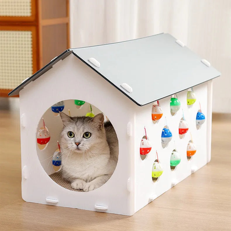 White plastic house-shaped cat scratch board with an integrated nest and a red bell ball toy inside.