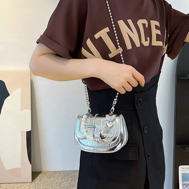 Women's silver mini crossbody bag with a square shape and a single shoulder strap.
