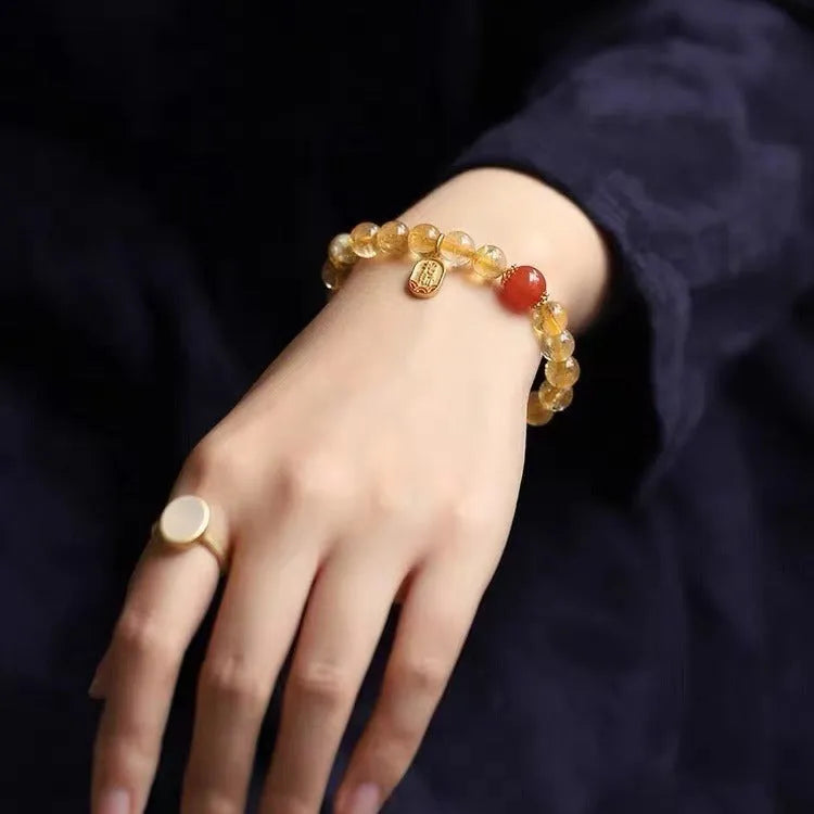 Natural red agate lucky beads bracelet with gold ruby accents on a wrist.