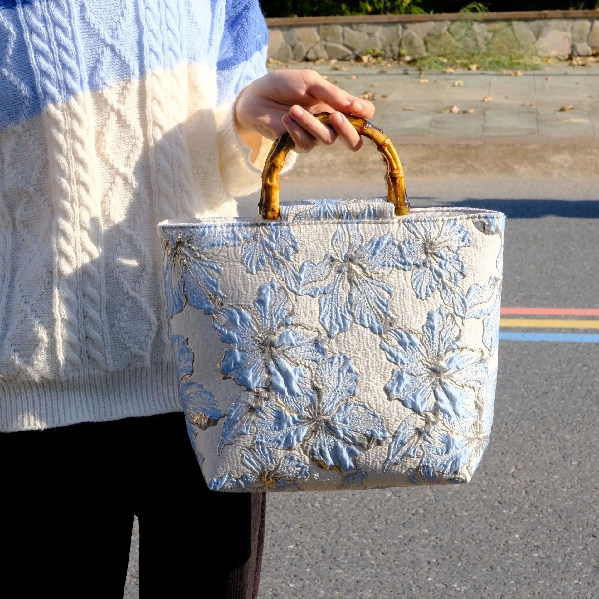 Light blue canvas bag with gold bronzing flower pattern, horizontal square shape, and dual shoulder straps.