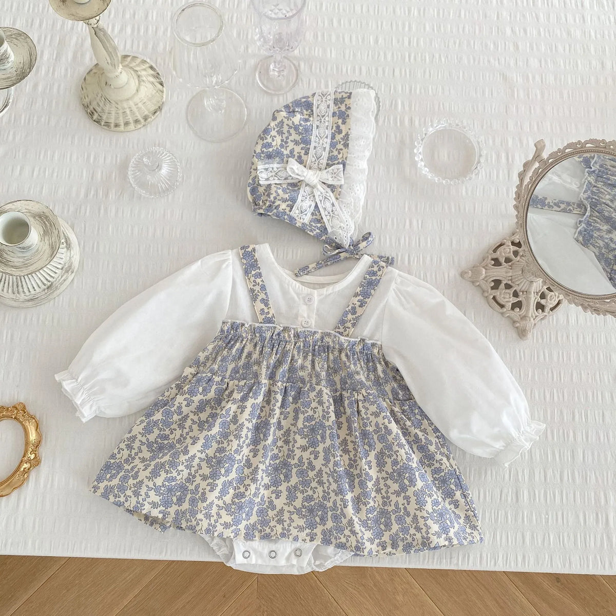 White cotton baby girls' floral princess romper with long sleeves, pullover closure, and removable hood in triangle jumpsuit style