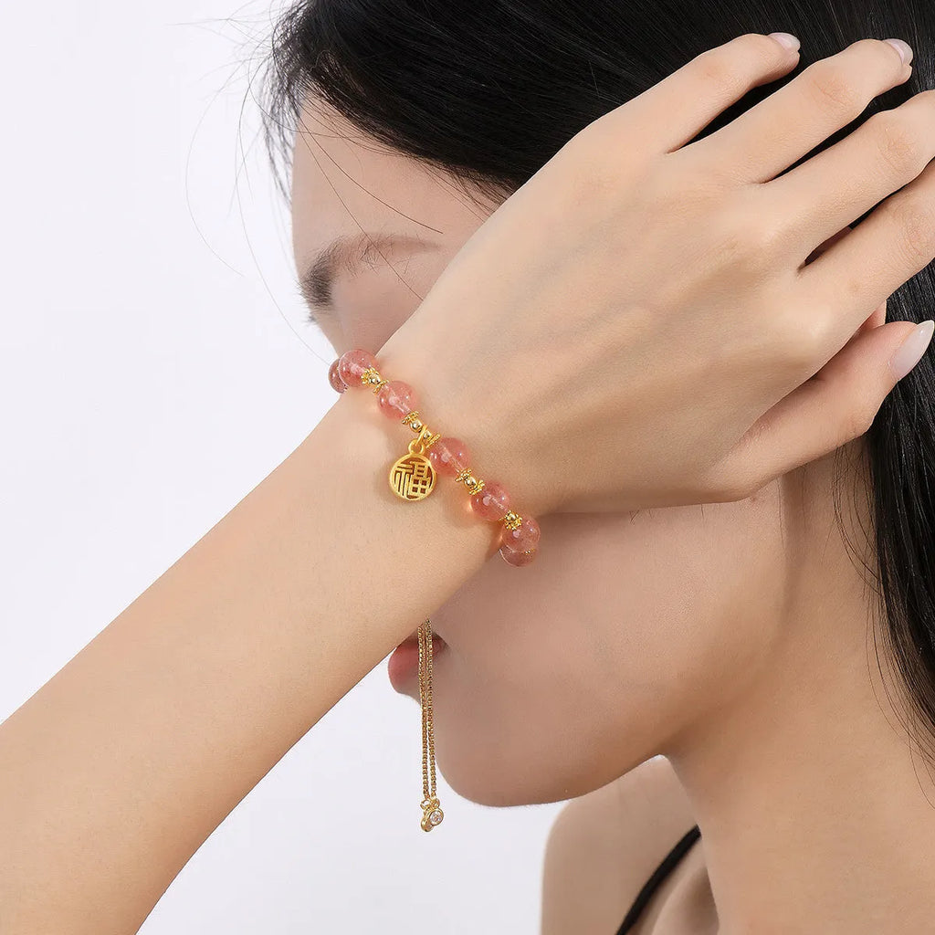 Women's Strawberry Quartz crystal bracelet with geometric design and fu character charm on wrist