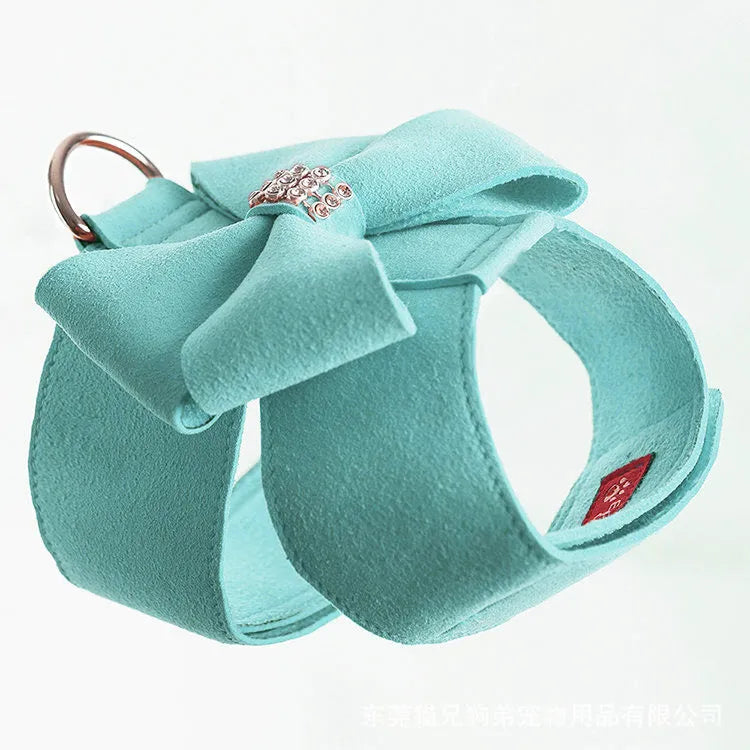 A pink dog harness with a white bow knot on an adjustable microfiber chest strap.