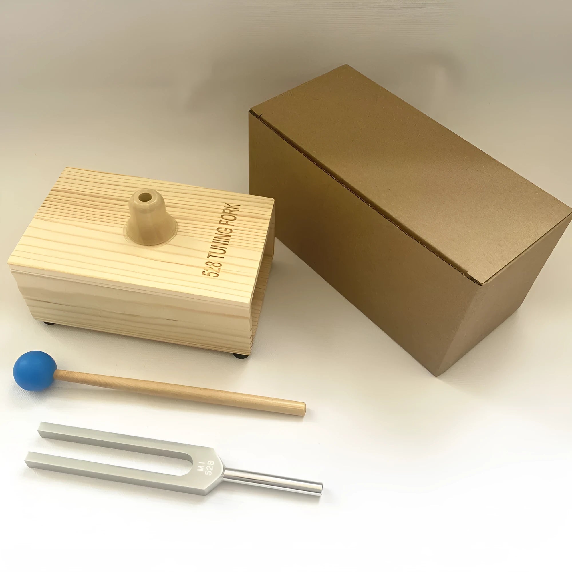 Aluminium alloy 432Hz tuning fork and speaker set on a kraft paper box.