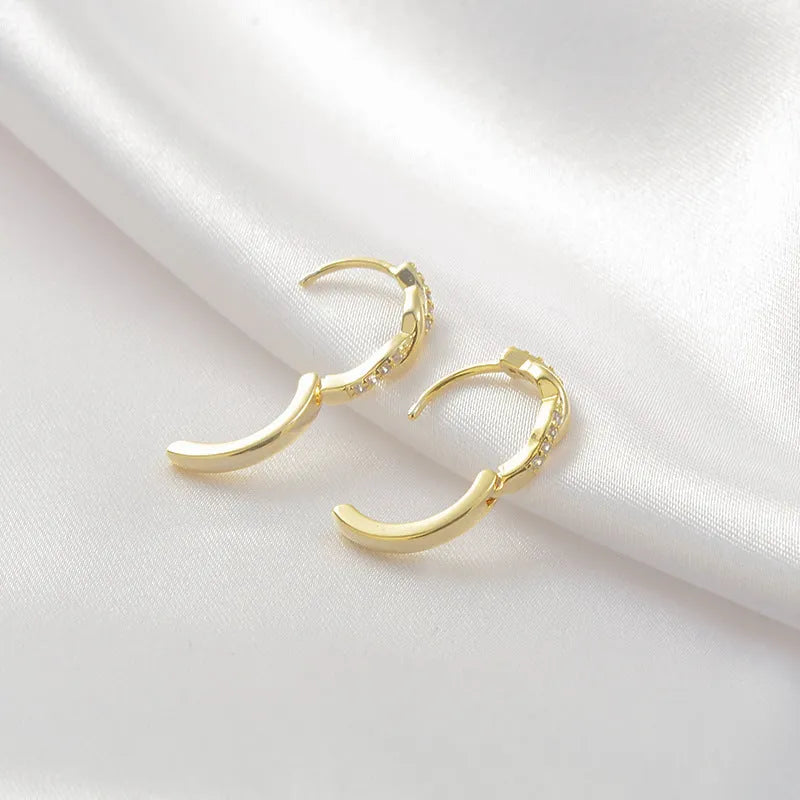 Close-up of women's geometric ear clips with interwoven hemp rope centre in gold tone.