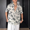 Loose fit floral printed short sleeve shirt in black, hanging on a hanger.