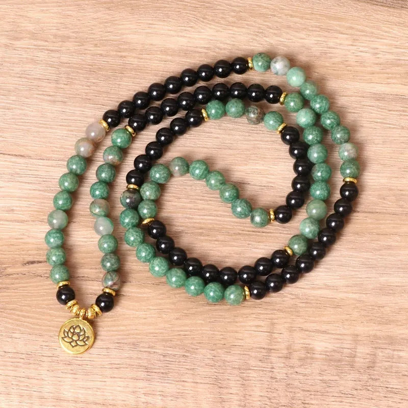 Green and black alloy bead long bracelet with elasticated band on a wrist.