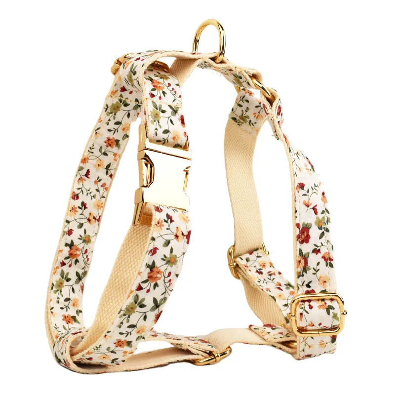 Small white flower pet dog collar set with matching vest, leash, bow, and accessories on a cloth background.
