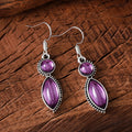 A pair of vintage-style geometric drop earrings with a round detail in black and purple electroplated zinc alloy.