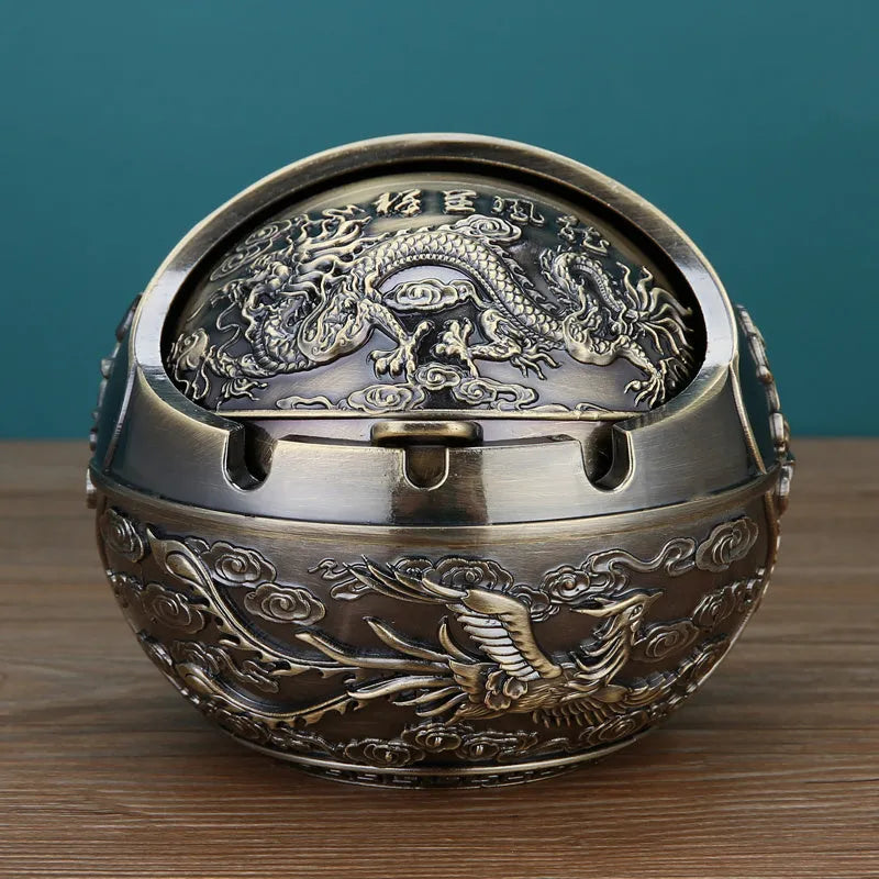 Bronze and red copper alloy decorative ashtray with smoke-extinguishing slot on a table.