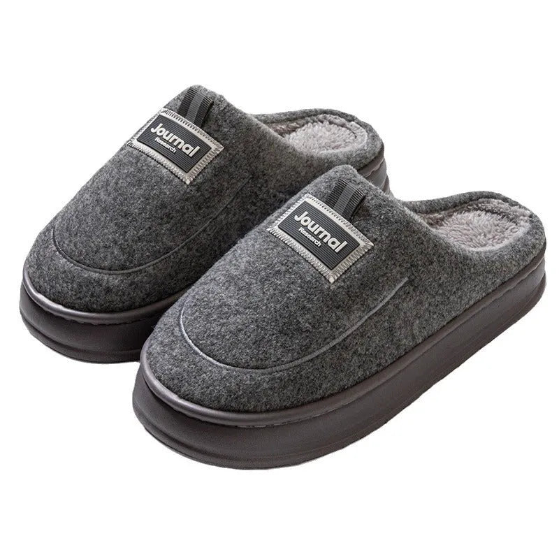 Men's brown suede slippers with a thick, textured sole on a wooden floor
