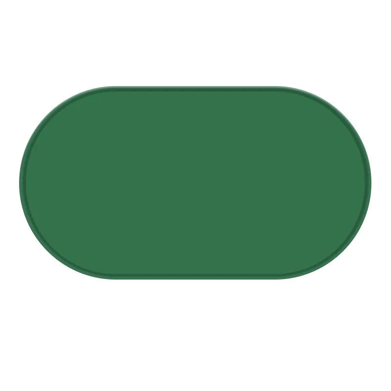Green silicone cat feeding mat with raised edge holding a food bowl and water bowl on a kitchen floor.