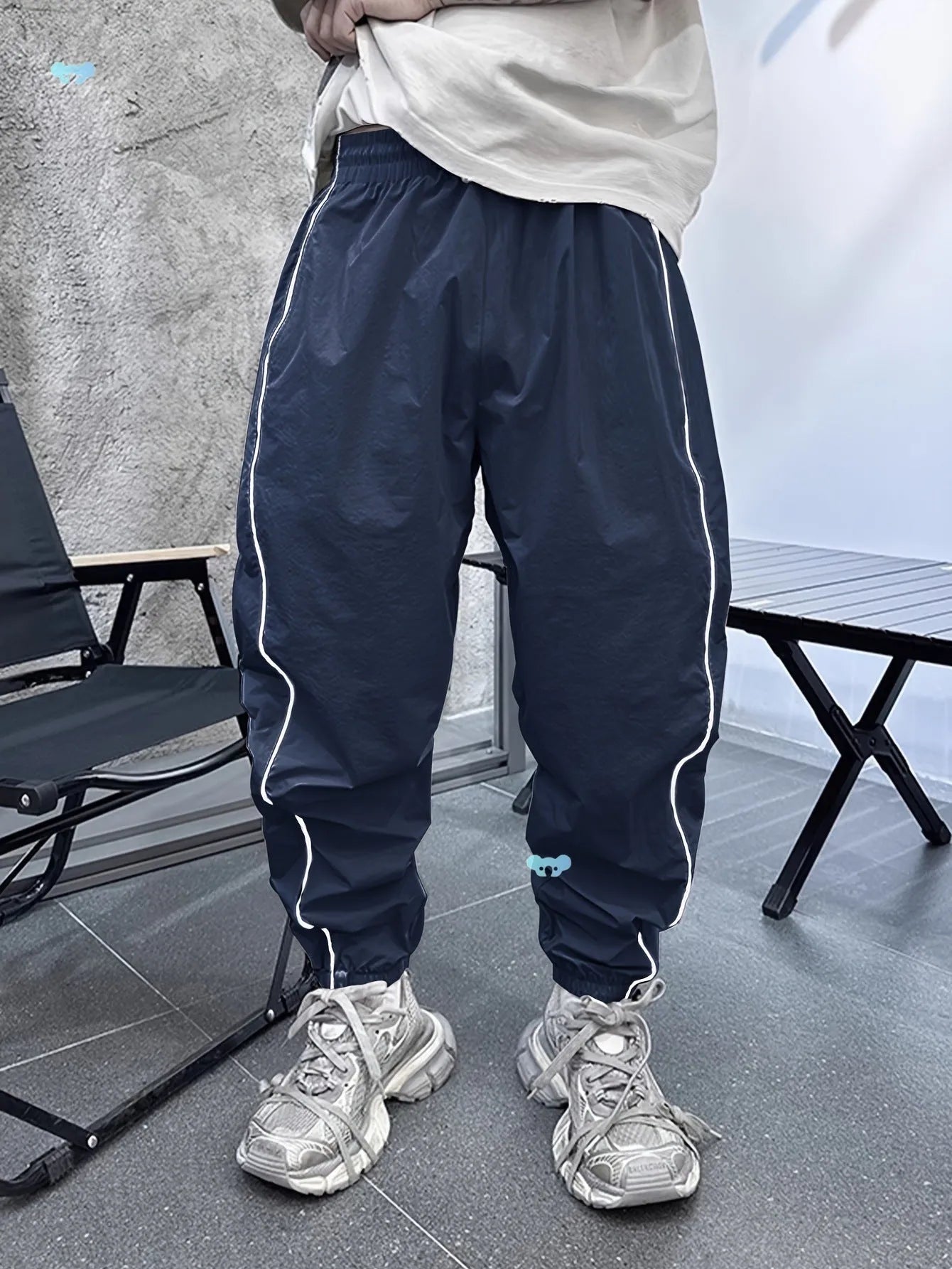 Man wearing loose-fit cropped sports trousers in bamboo fibre, showing army green colour and elastic waist.