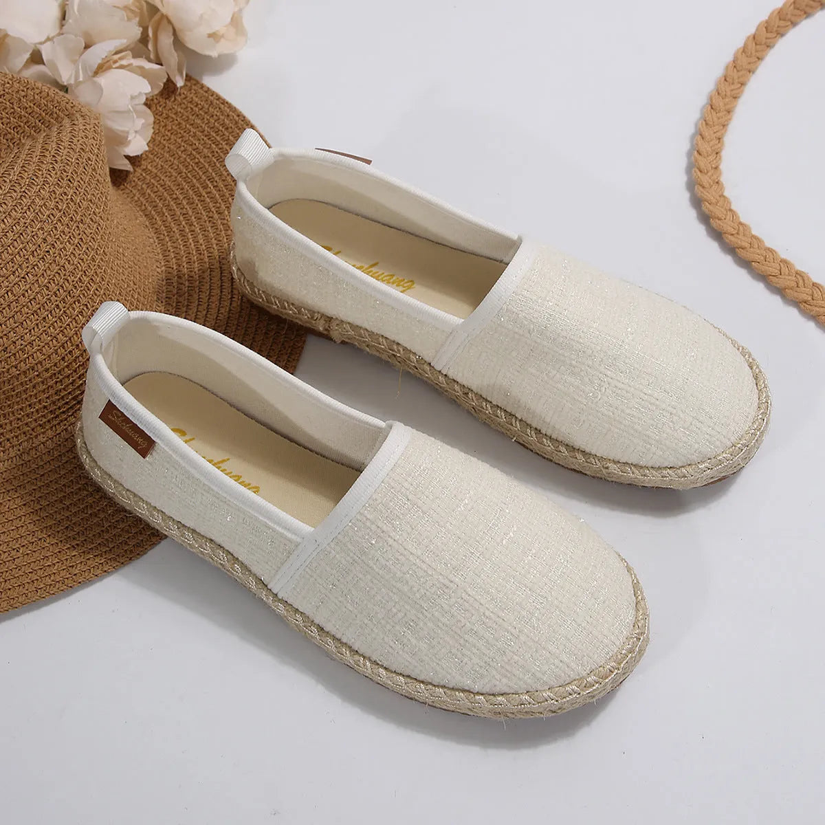 Casual beige canvas fisherman shoes with a textured rope sole on a wooden floor.