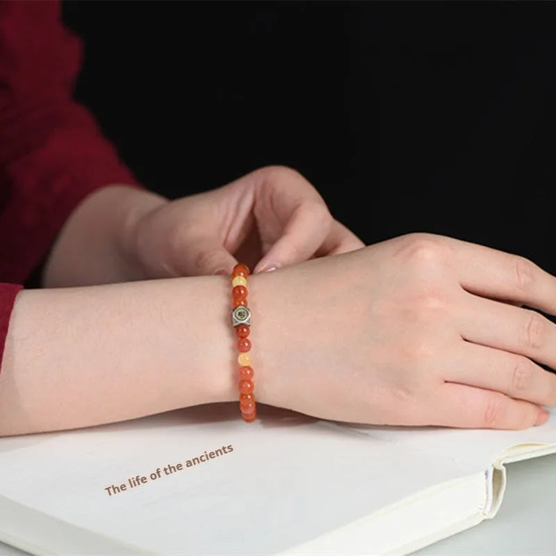 Natural red Nanhong agate zodiac bracelet with a yellow beeswax bead on a wrist.