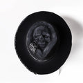 Handmade black wool felt skull hat with conical crown and blue denim accent band, shown from the side.