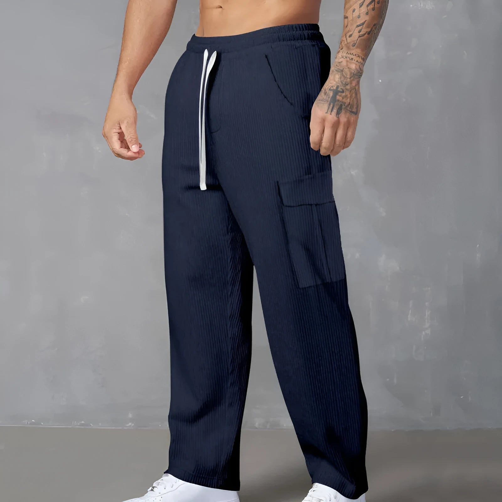 Man wearing navy blue loose-fit corduroy cargo trousers with a drawstring waist.