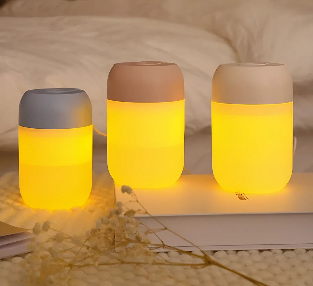 White cylindrical mini humidifier with USB cable on a wooden surface.