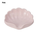 White or pink plastic shell-shaped soap dish for bathroom use on a counter.
