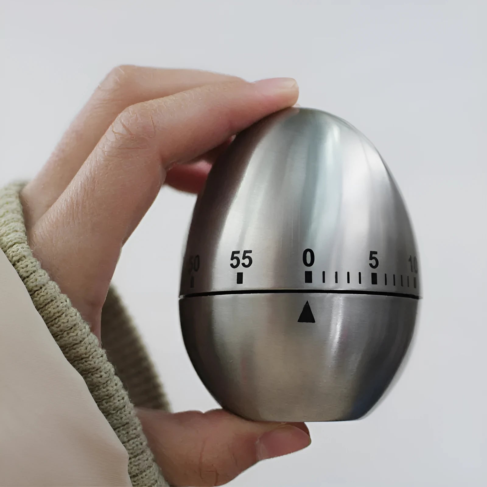 Stainless steel egg-shaped mechanical kitchen timer on a kitchen countertop