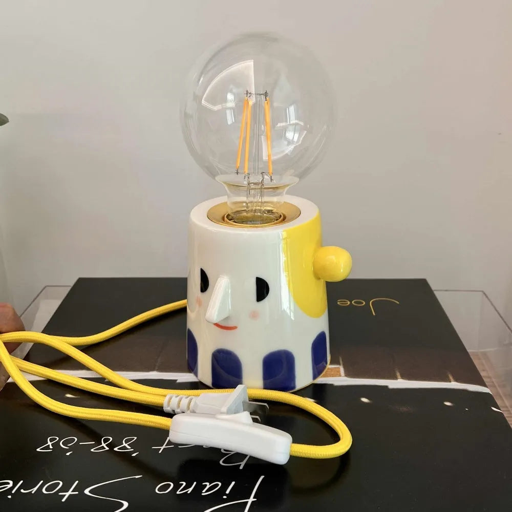 Handmade ceramic bedside lamp with white ball headlight shade on a wooden table.