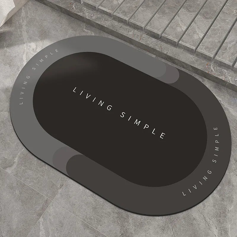 Oval grey polyester door mat with textured rubber non-slip backing on a wooden floor.