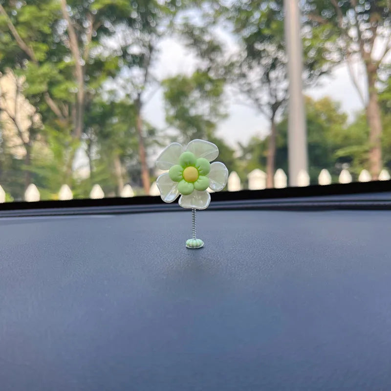 Small colourful plastic swing car decoration hanging from a rear-view mirror, showing blue, green, pink, purple, and yellow colour options.