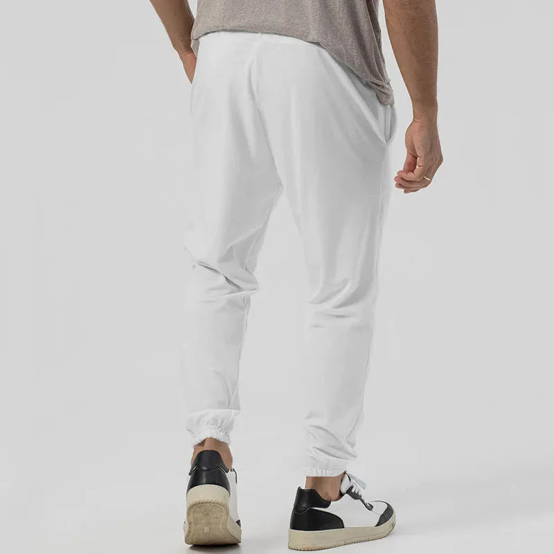 Man wearing grey straight-leg tapered sweatpants, showcasing the mid-rise waist and casual fit.