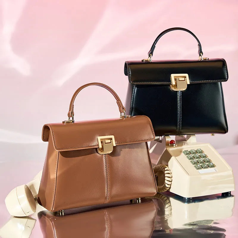 Black genuine leather women's shoulder bag with vachette clasp, showing horizontal square shape and adjustable strap.