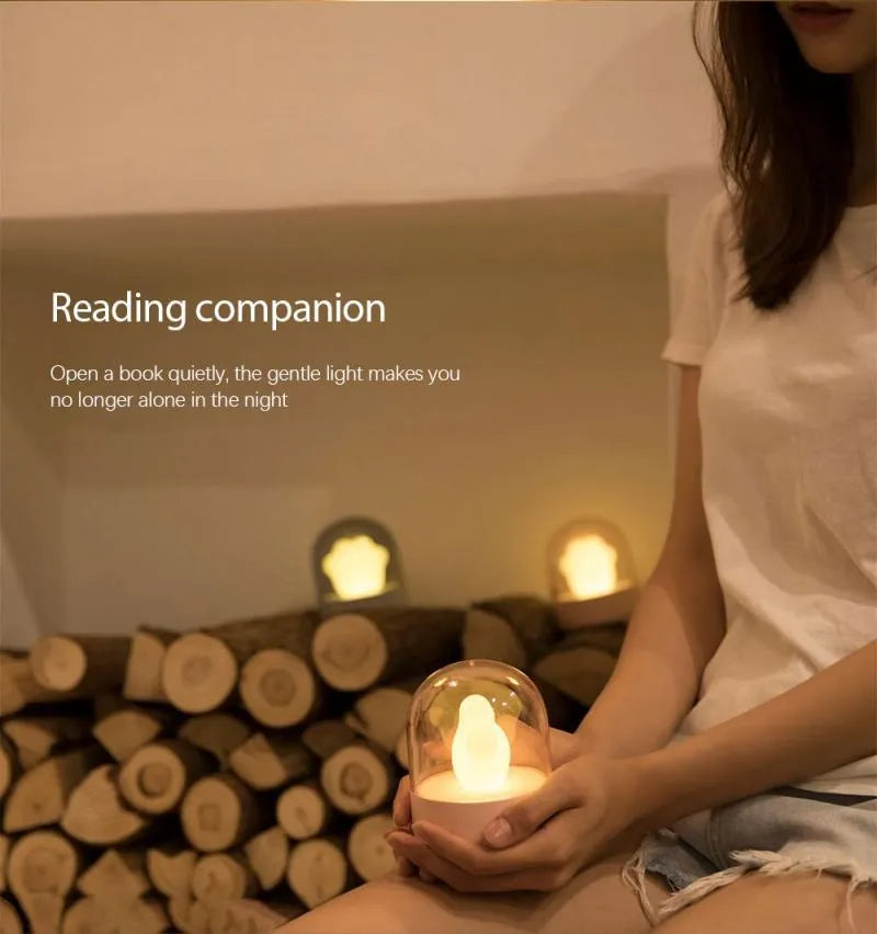 Pink cat paw shaped USB rechargeable night light with soft glow on a desk.