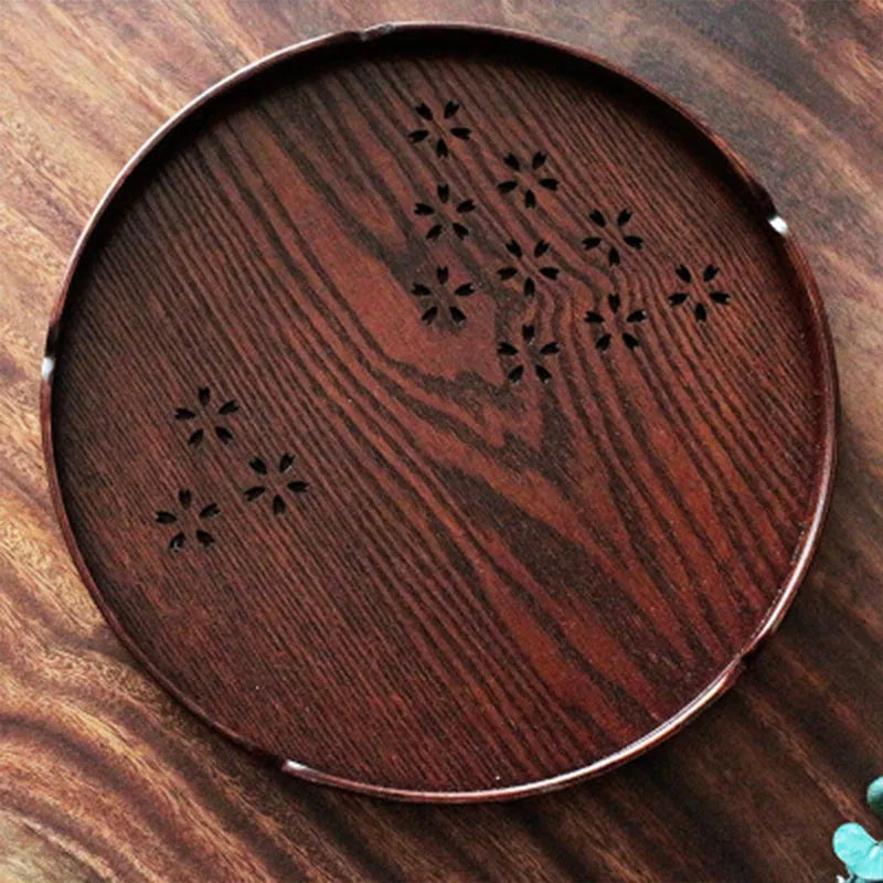 Wooden shallow plate with carved hollow cherry blossom pattern, shown from above.