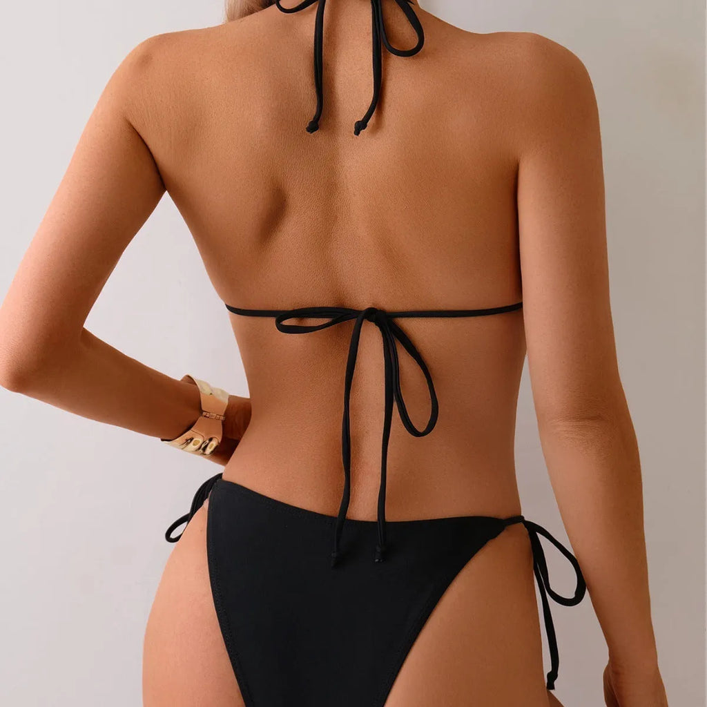 Black women's bikini swimsuit with metal bead details and a split design.