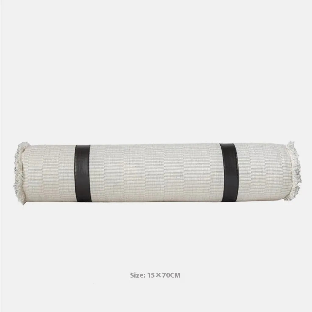Grey and white plaid bed runner blanket with matching pillowcase and brown leather round pillow on a bed.