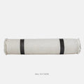 Grey and white plaid bed runner blanket with matching pillowcase and brown leather round pillow on a bed.