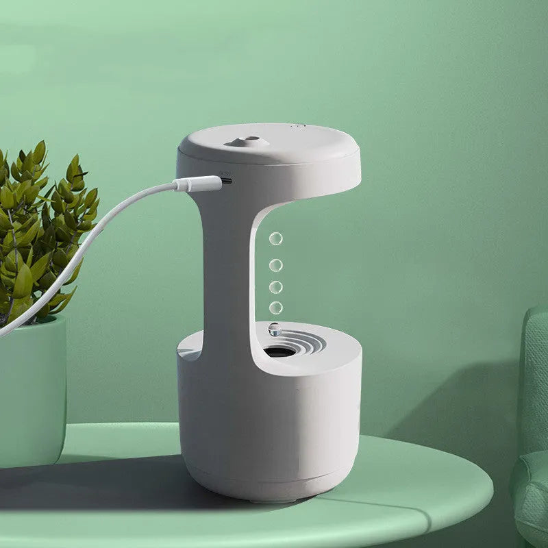 White columnar anti-gravity humidifier with LED clock display and mist output on a wooden desk.