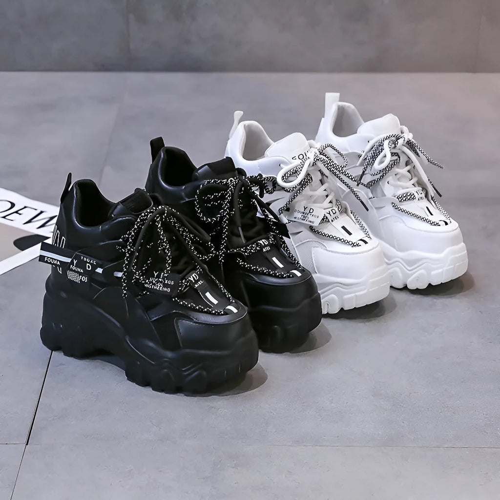 Women's white mesh platform sports shoe with cross strap and rubber sole on a neutral background.