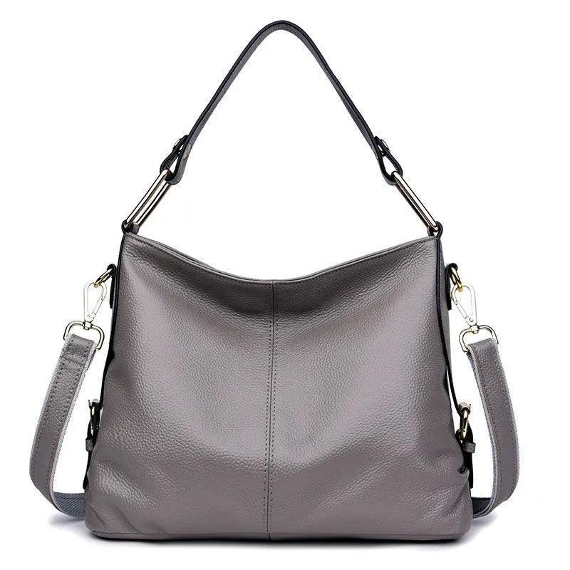 Genuine leather vertical square crossbody bag in black with sewing line detail and external pocket.