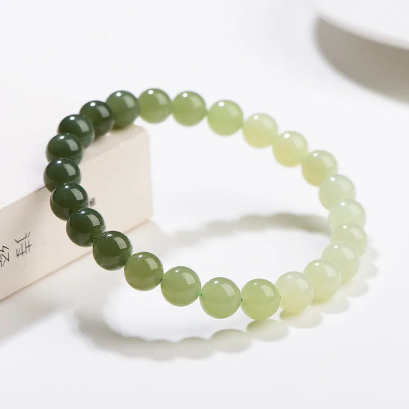 Natural Hetian jade bracelet with gradient clear water colour beads on a wrist.