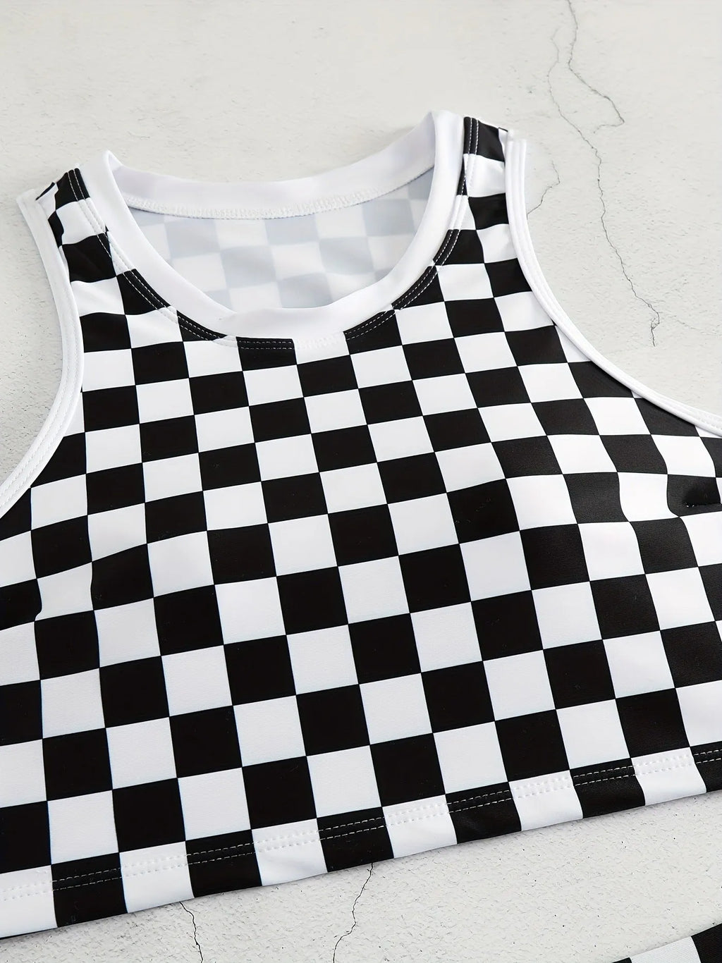 Women's black and white checkerboard plaid backless racing swimsuit with suspender straps.