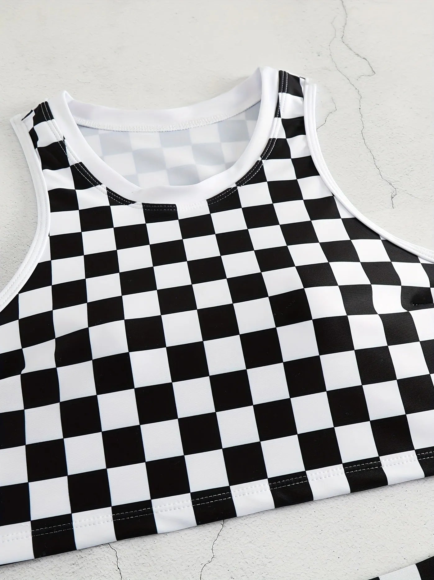 Women's black and white checkerboard plaid backless racing swimsuit with suspender straps.