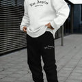 Man wearing a grey hooded zip-up jacket and matching trousers from a winter sports sweatsuit set.