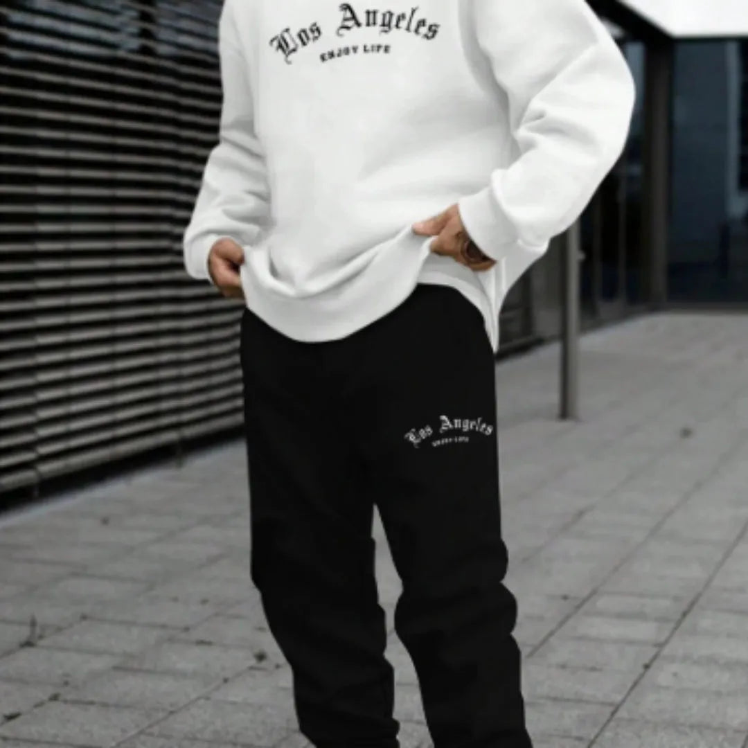Man wearing a grey hooded zip-up jacket and matching trousers from a winter sports sweatsuit set.
