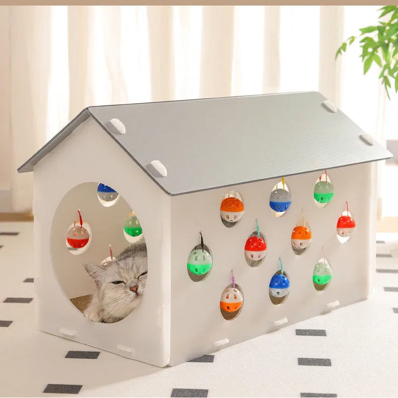 White plastic house-shaped cat scratch board with an integrated nest and a red bell ball toy inside.