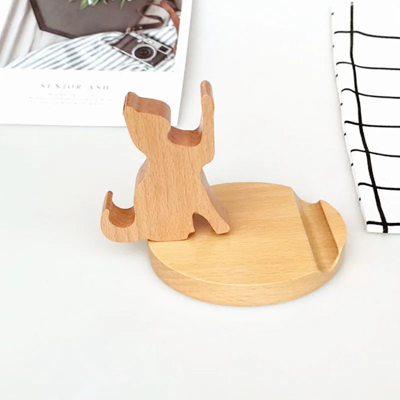 Sculpted beech wood lazy bracket phone holder with custom engraved text on a wooden desk.
