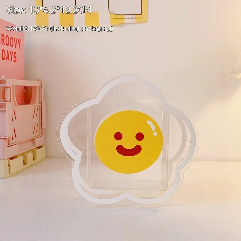 Clear square acrylic storage box with a colourful printed lid featuring a cute design, shown holding pens and stationery.